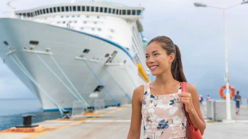 woman standing on a dock with a large cruise ship in the background